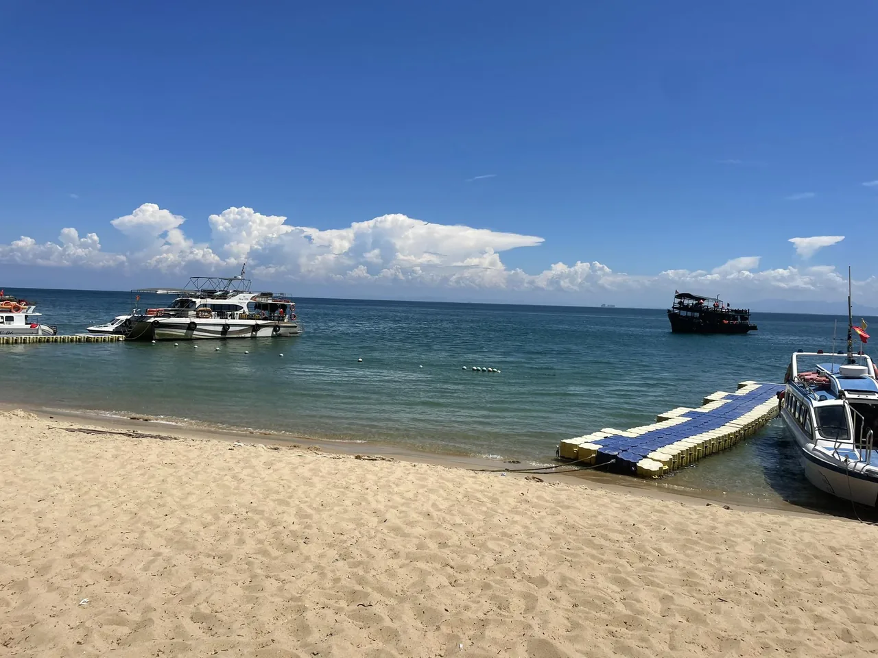 Speedboats and a floating jetty on a sandy Cu Lao Cham beach with clear blue water