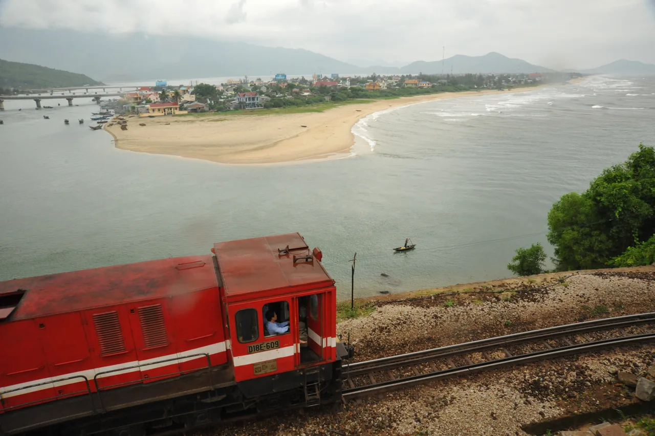 A red Vietnam Railways train curving above Lang Co bay on the Da Nang to Hue railway line