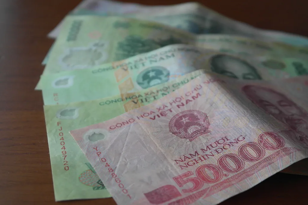 Vietnamese dong banknotes fanned out on a wooden table, illustrating Da Nang travel costs