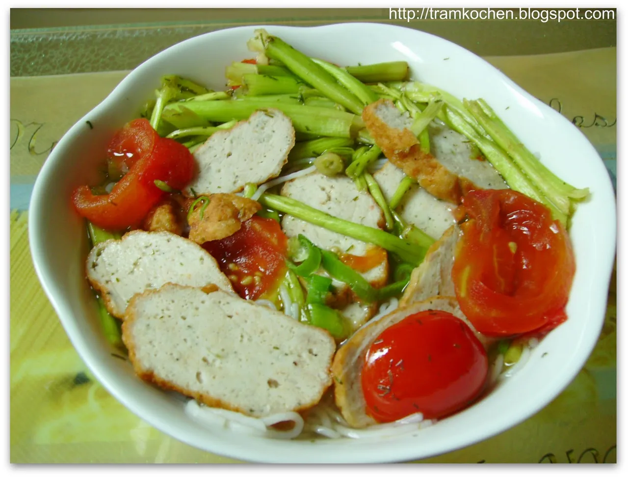 A bowl of bún chả cá served with a plate of fresh herbs