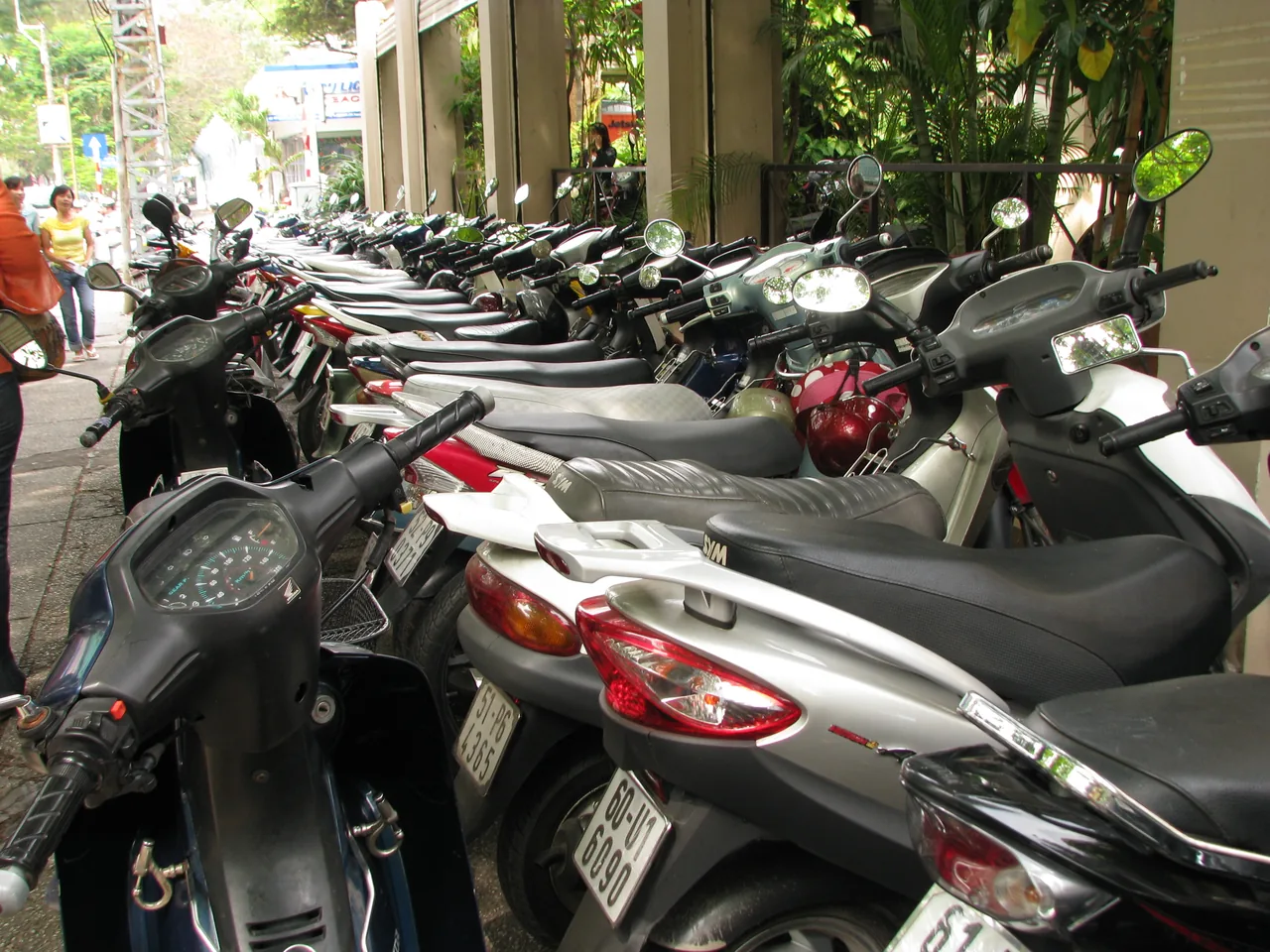A row of scooters and motorbikes parked on a Vietnamese street