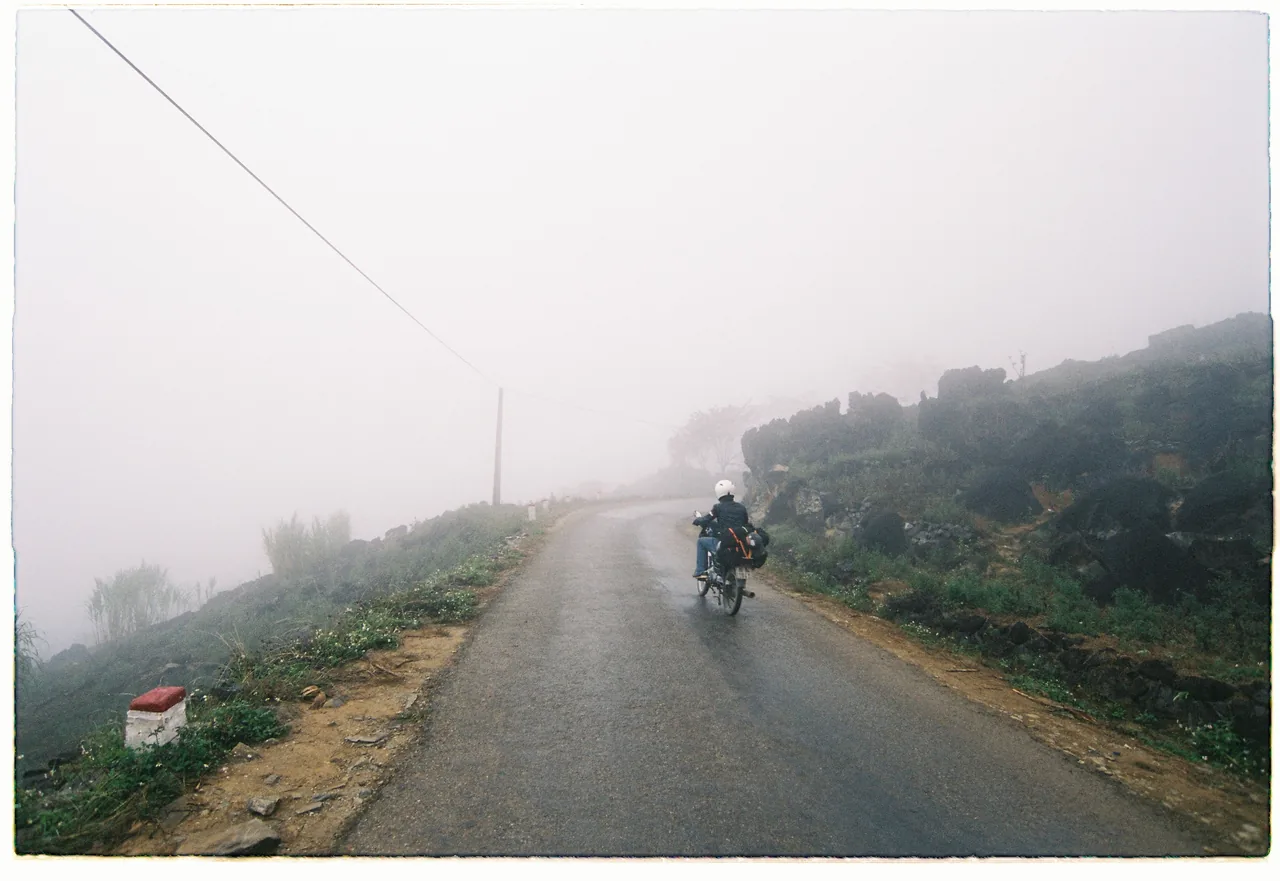 A motorbike rider on the Ha Giang Loop with limestone karst mountains in the background A motorbike rider on the Ha Giang Loop with limestone karst mountains in the background