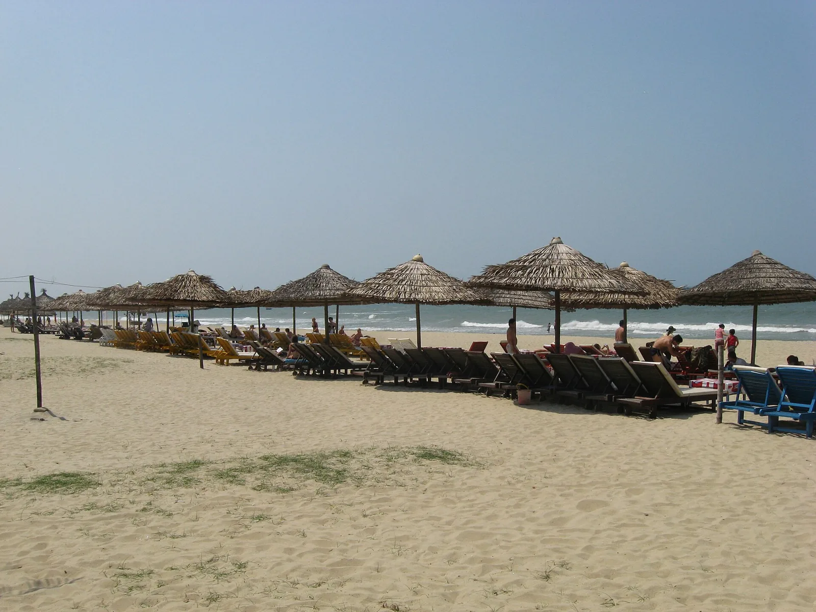 Rows of thatched parasols and sun loungers on a Hoi An beach Rows of thatched parasols and sun loungers on a Hoi An beach