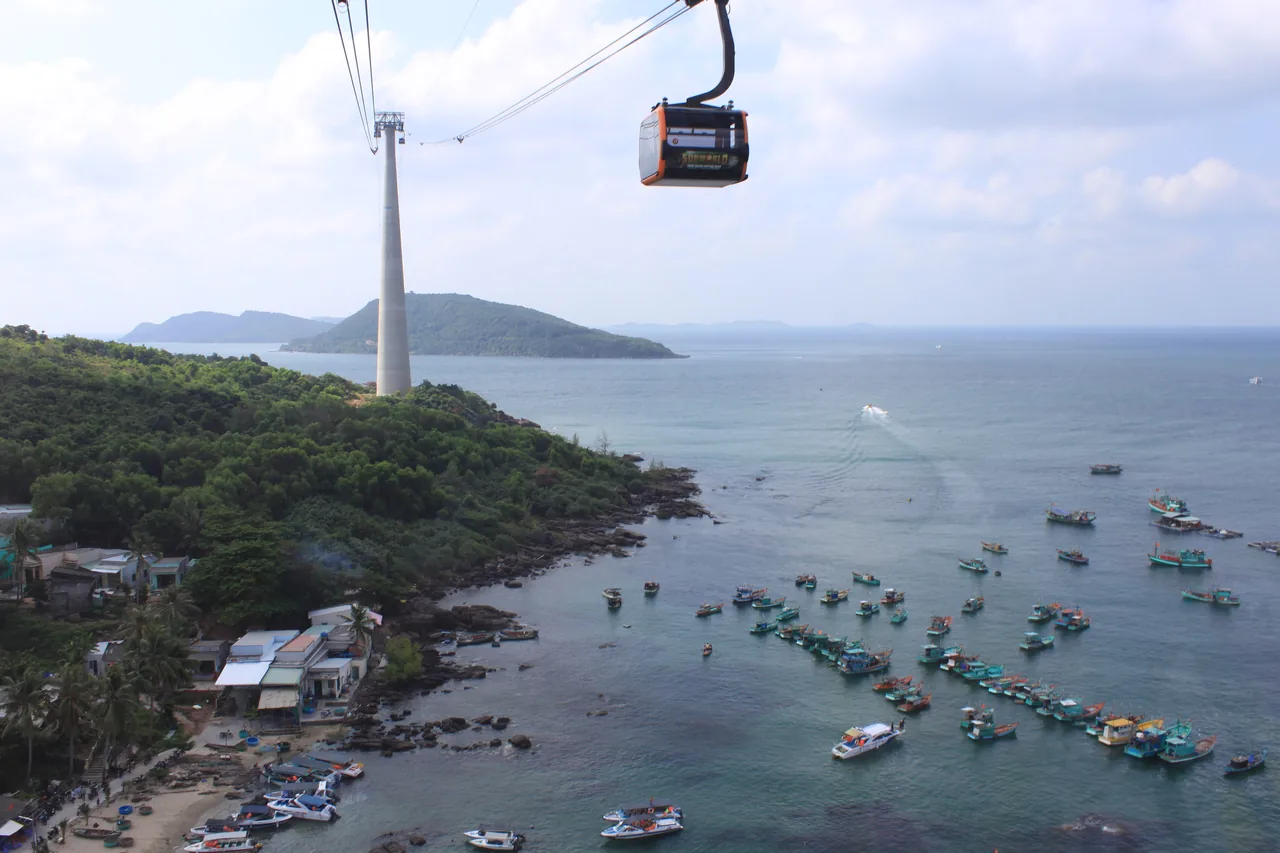 緑の島々と漁船の上を青い海を渡るケーブルカーのゴンドラ