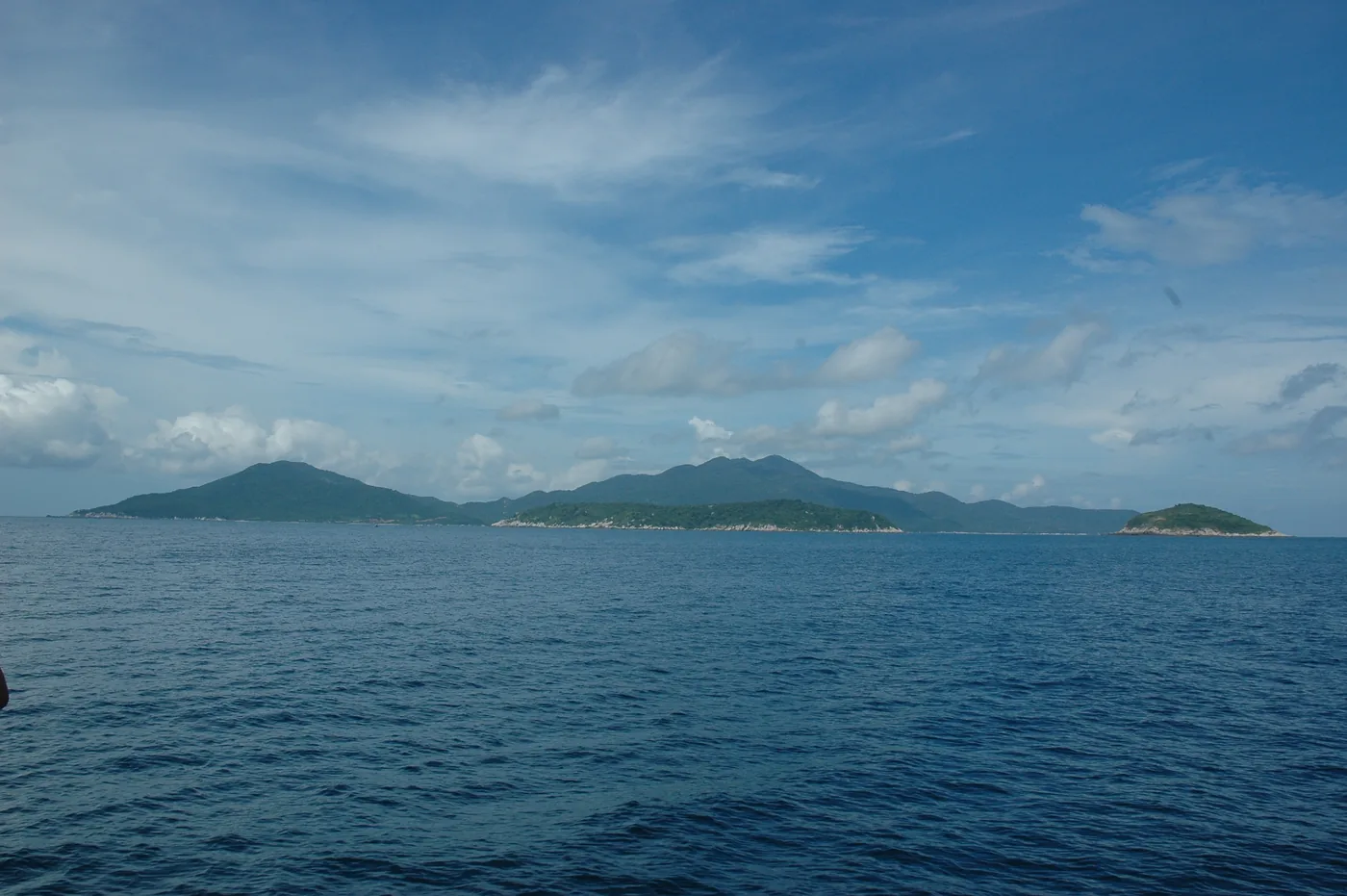 The Cù Lao Chàm island group seen low from the sea, a long green ridge with a smaller islet to the right