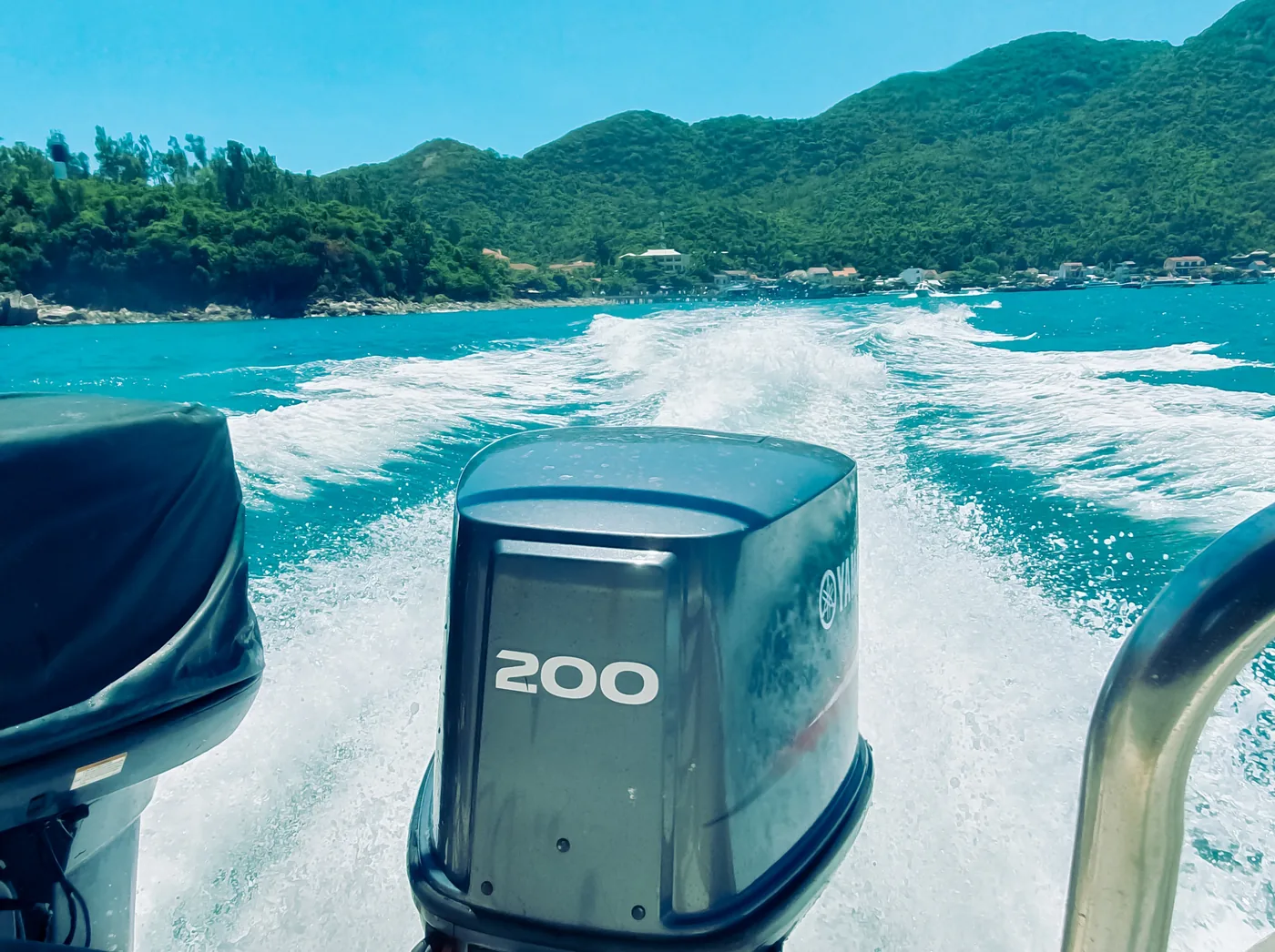 Two black outboard motors and a churned white wake seen over the stern of a speedboat crossing to Cù Lao Chàm