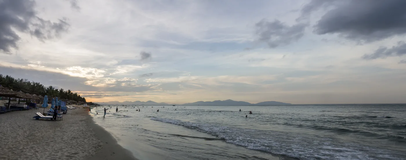 Cửa Đại beach at dusk with rows of sun-loungers and closed parasols, and the islands low on the horizon