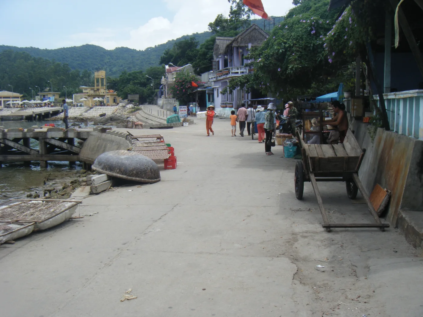 Upturned round basket boats and a wooden two-wheeled handcart on the village waterfront promenade