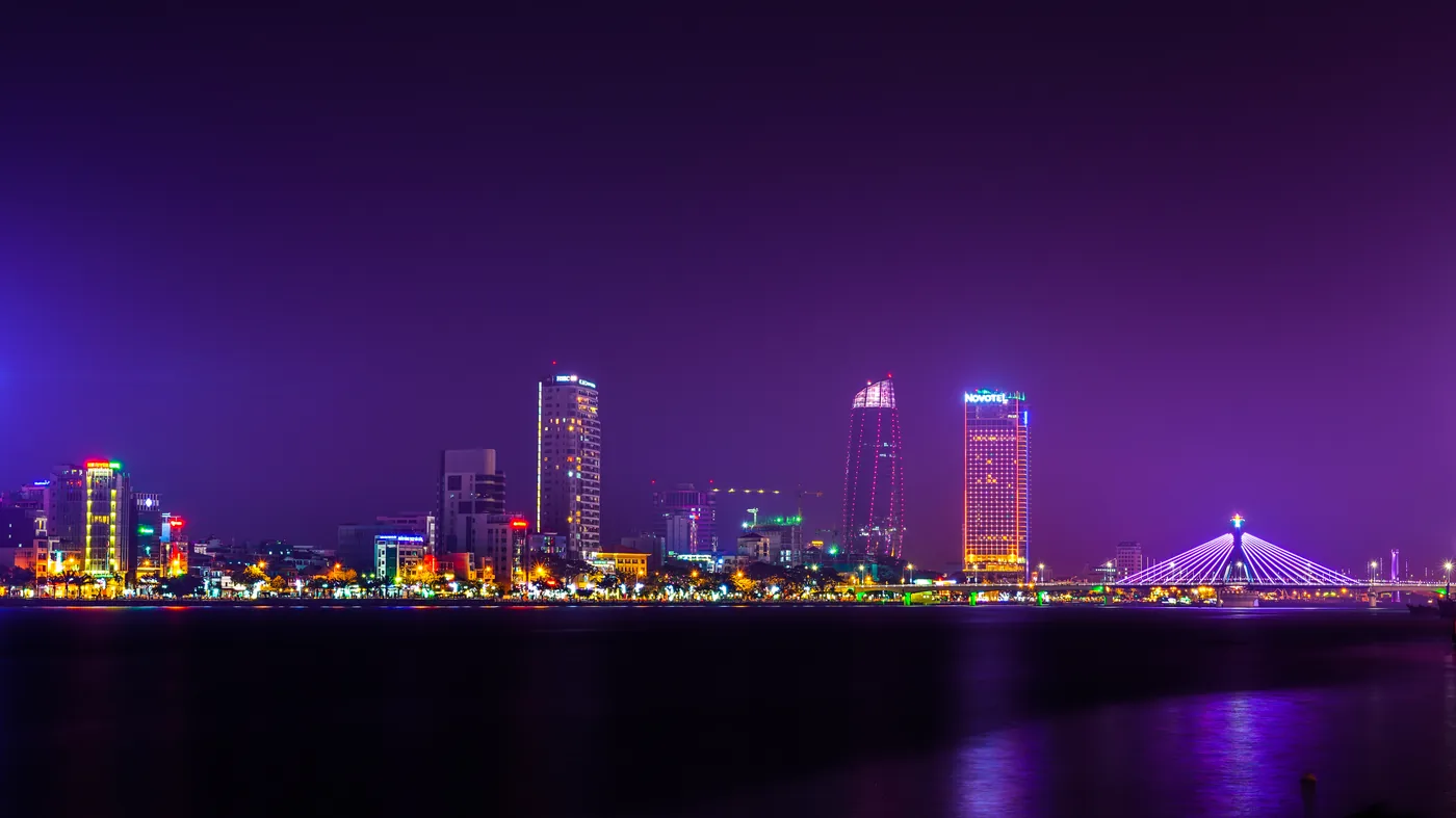The Da Nang skyline and Han River lit up at night, with the Han River Bridge on the right