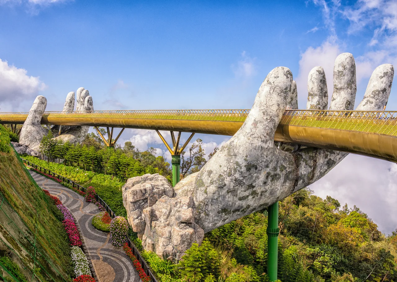 The Golden Bridge held by two giant stone hands at Ba Na Hills on a clear day