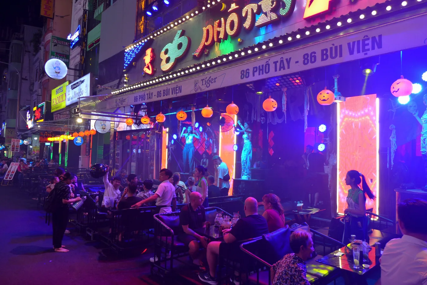 A Ho Chi Minh City street eatery lit up at night with diners at low tables