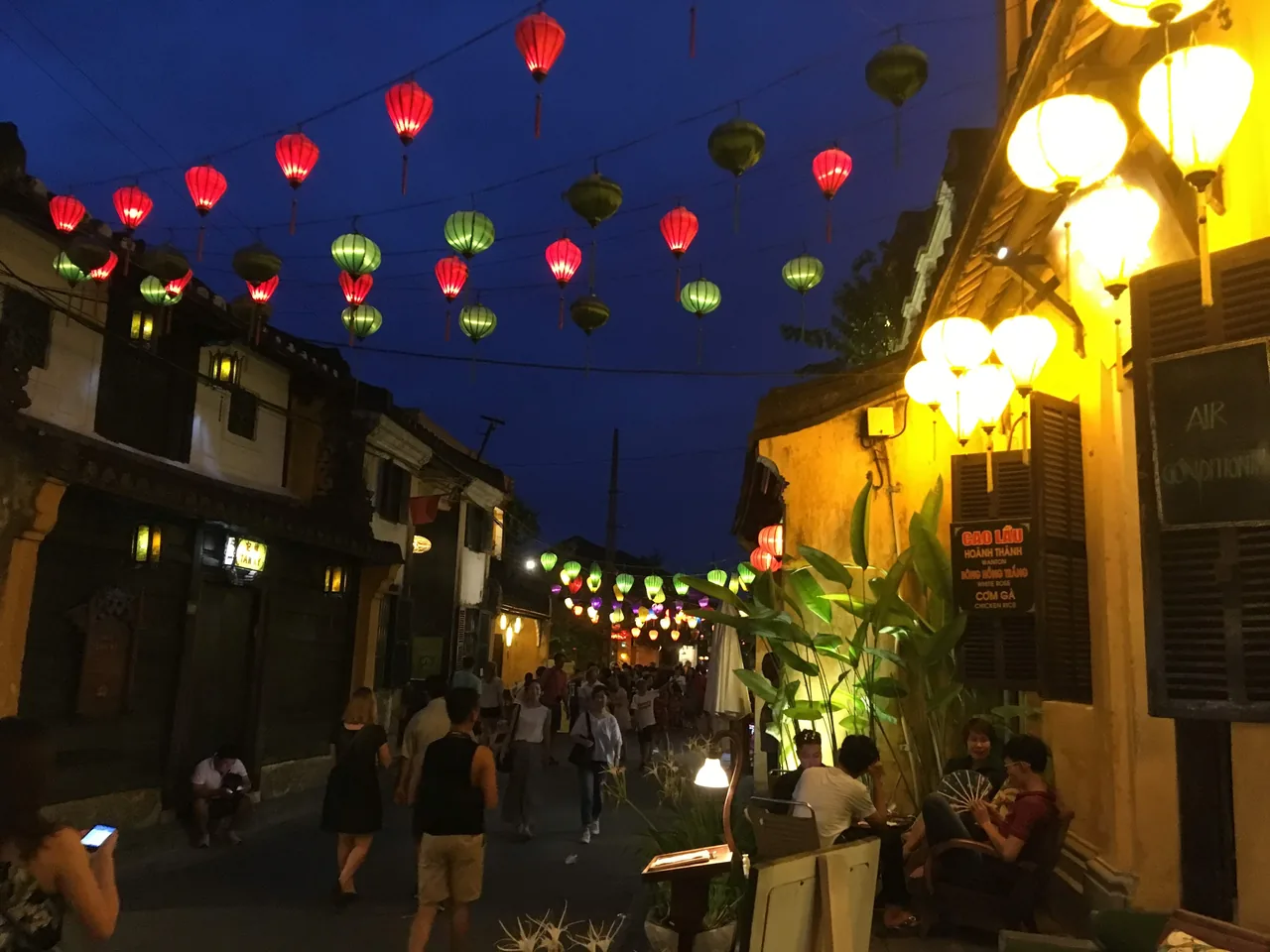 Silk lanterns glowing over a Hoi An Ancient Town street at dusk