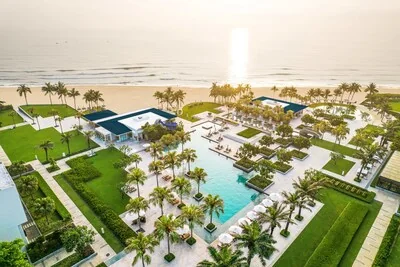 An outdoor swimming pool at Hyatt Regency Danang Resort and Spa at sunset, with the beach beyond