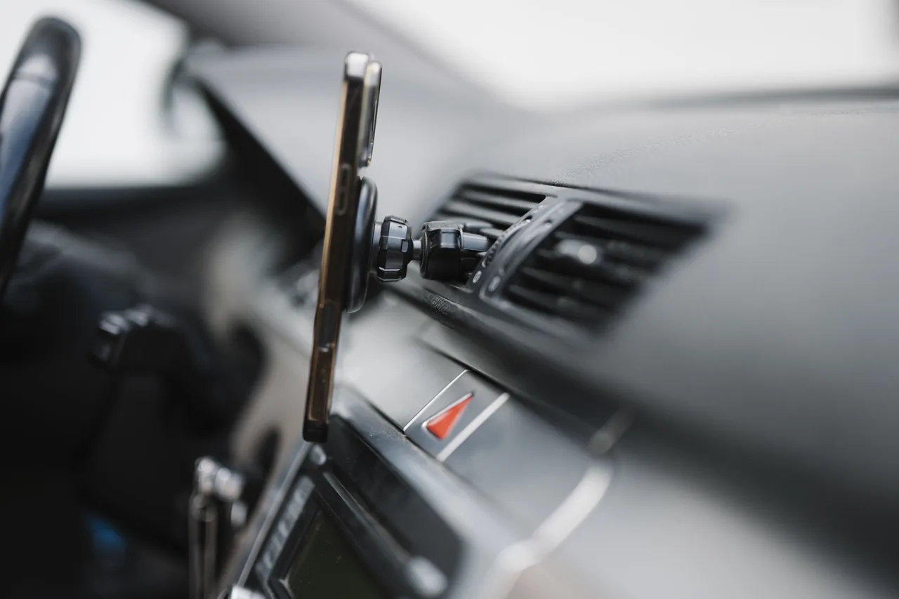 A smartphone mounted on a car dashboard showing navigation during a ride