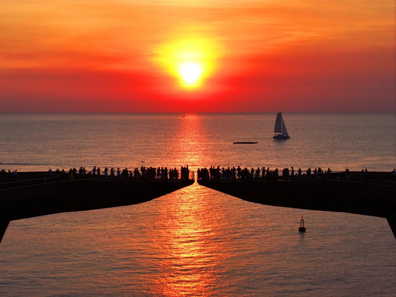 夕焼けに染まるキスブリッジの遊歩道を歩く、シルエットの観光客たち。 夕焼けに染まるキスブリッジの遊歩道を歩く、シルエットの観光客たち。