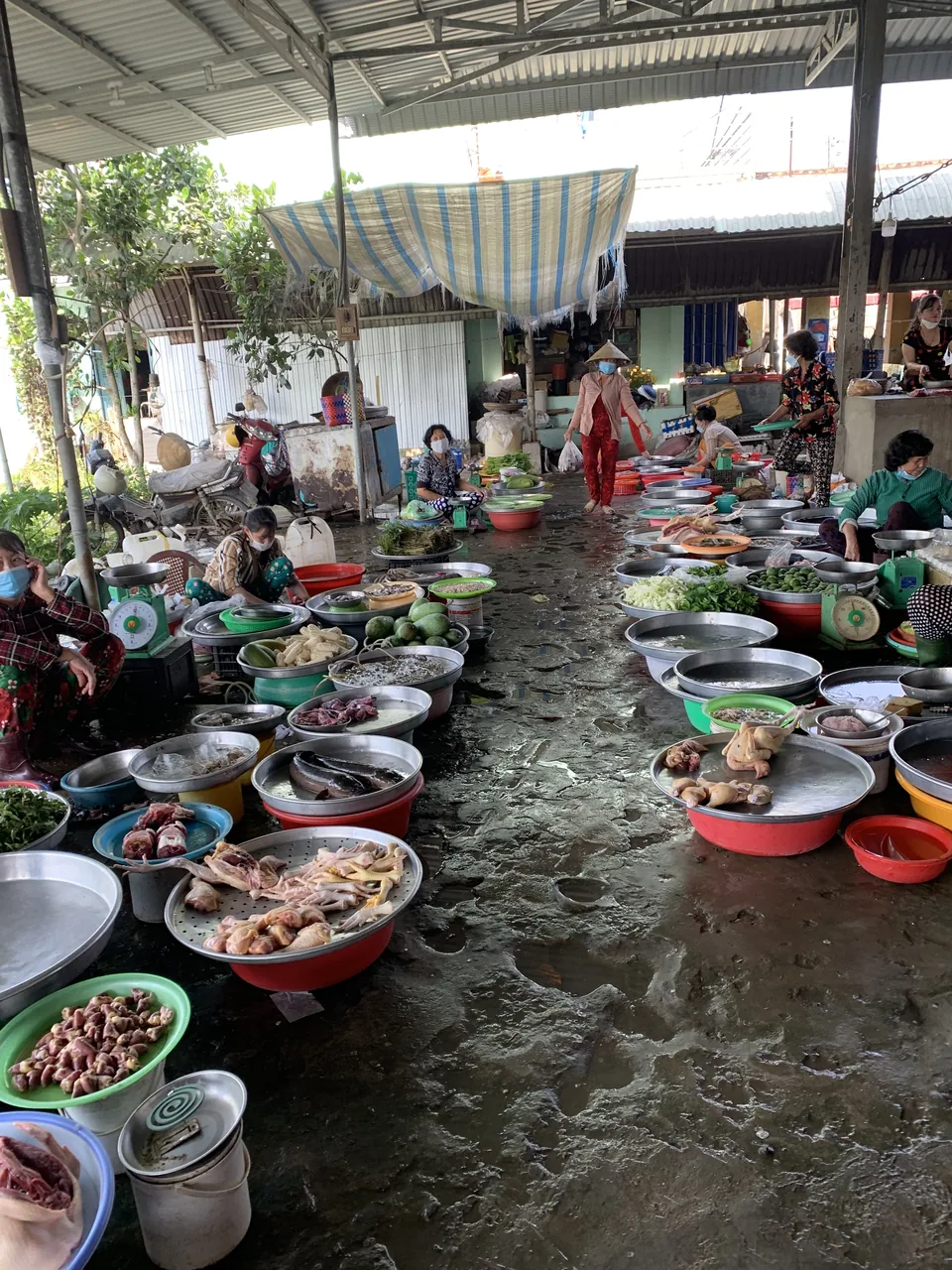 A bustling Vietnamese wet market with vendors, fresh produce and shoulder-pole baskets.