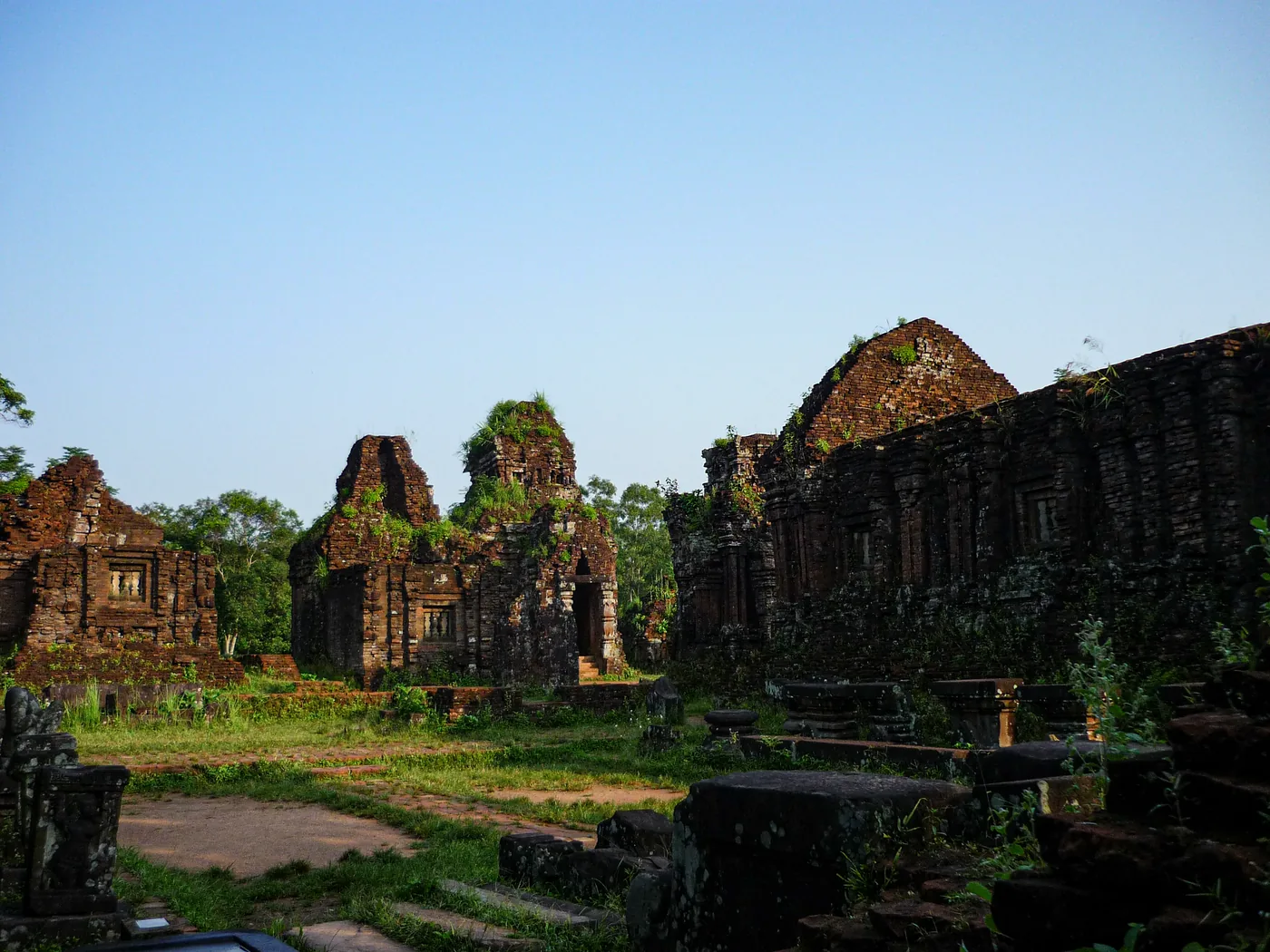 Weathered red-brick Cham Hindu towers of the My Son Sanctuary standing in a jungle valley.