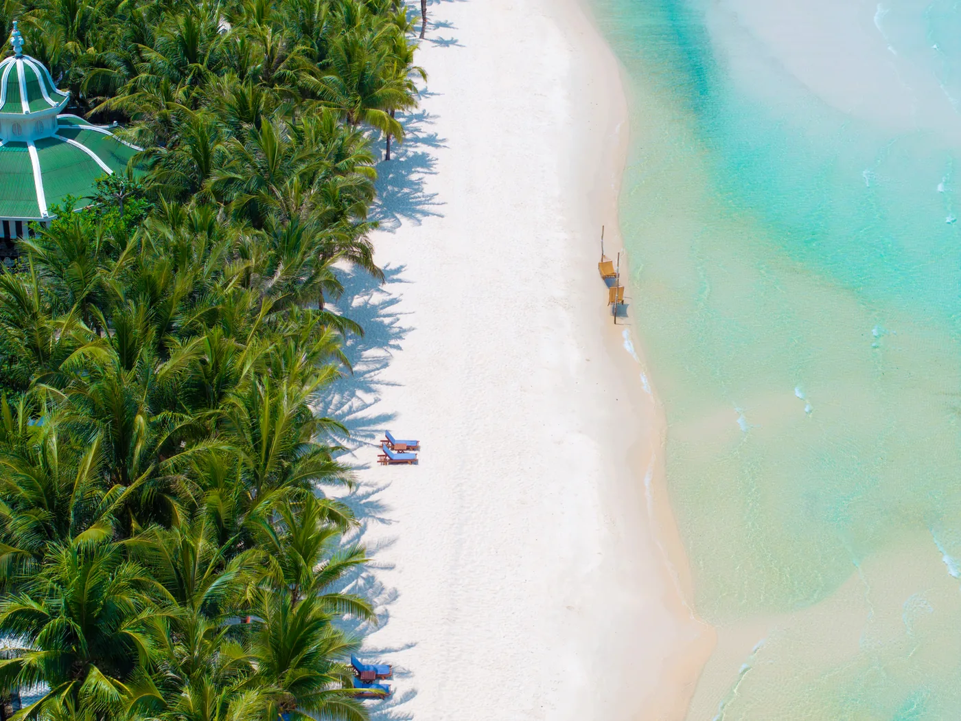 A quiet white-sand beach on Phu Quoc island fringed with palms and calm turquoise water.