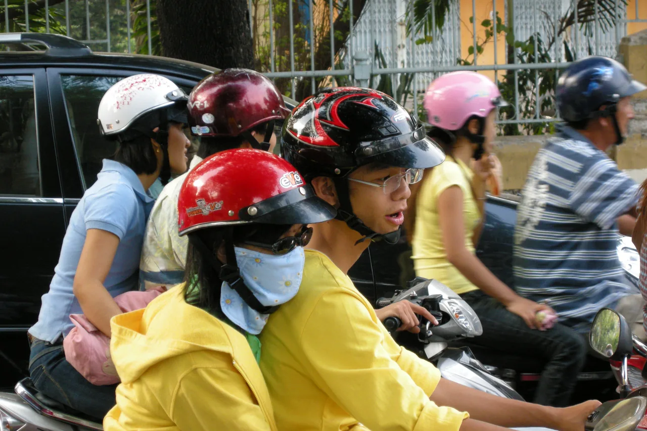 A dense river of motorbikes flowing through a Vietnamese city intersection at rush hour.