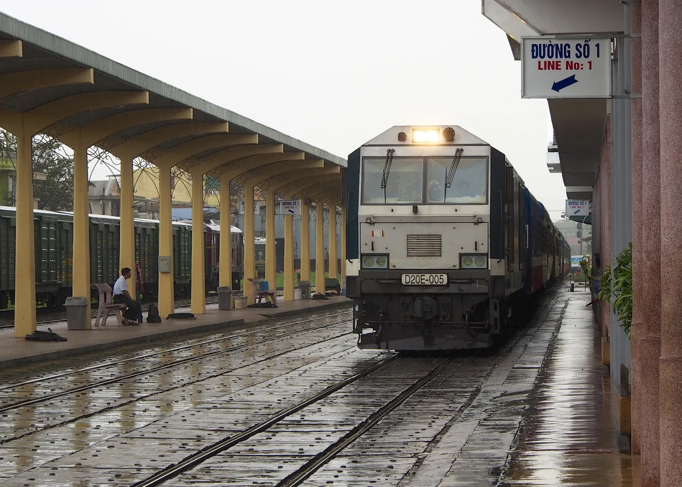 A Reunification Express carriage curving along the coast on the Hai Van Pass rail line between Hue and Da Nang, ocean on one side.