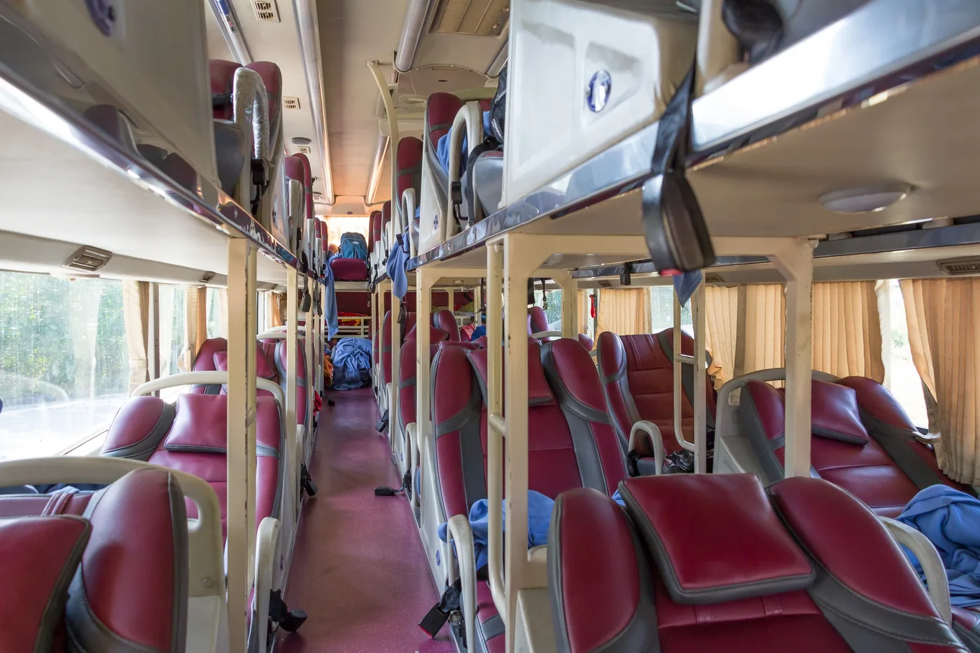 A Vietnamese sleeper bus interior showing rows of curtained berths on two levels with shoes stored at the foot of each bunk