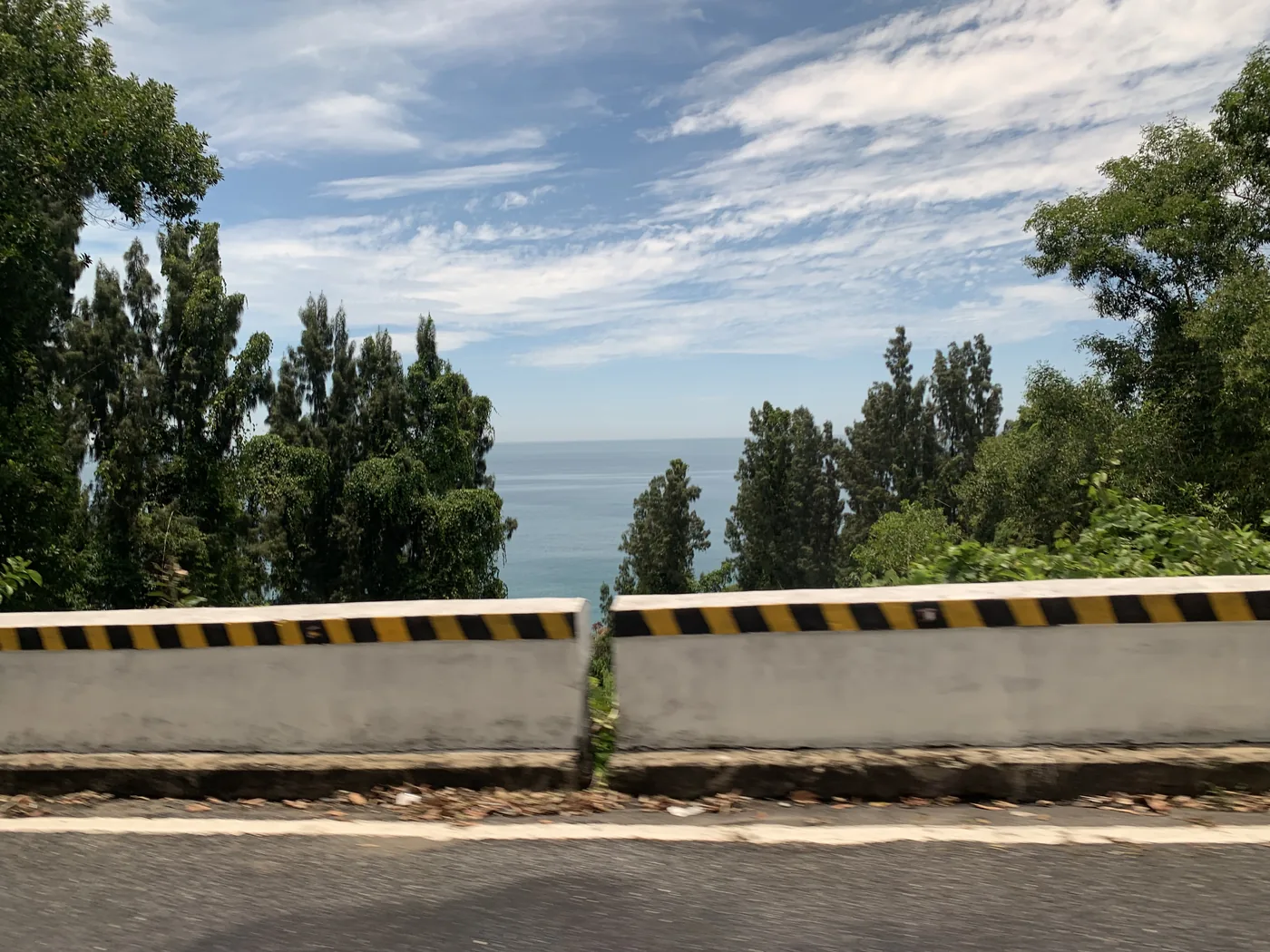 A stretch of Vietnamese expressway with light traffic running between hills under a wide sky