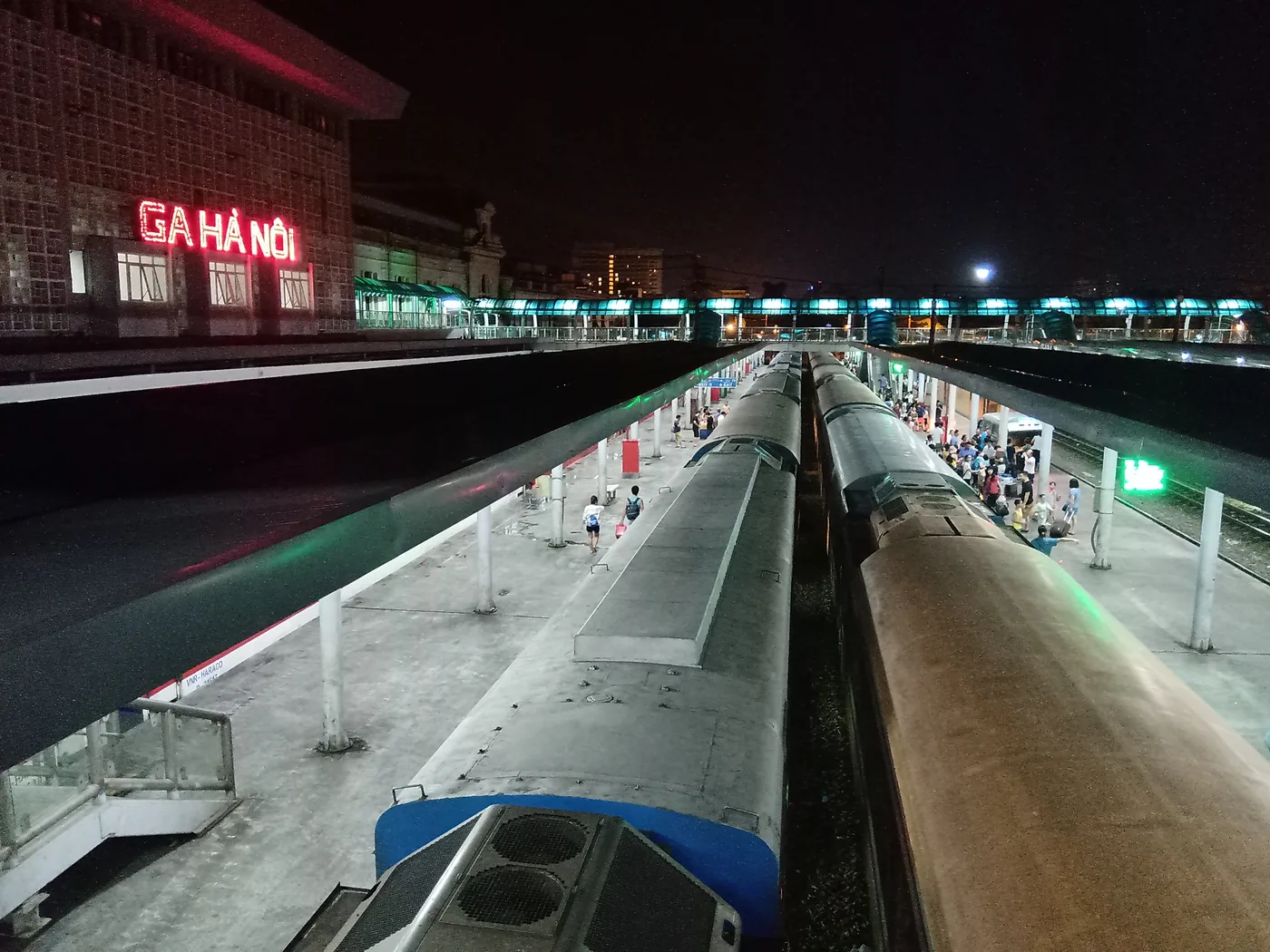 The platform and ticket hall of a main Vietnamese railway station with passengers waiting beside a stationary train