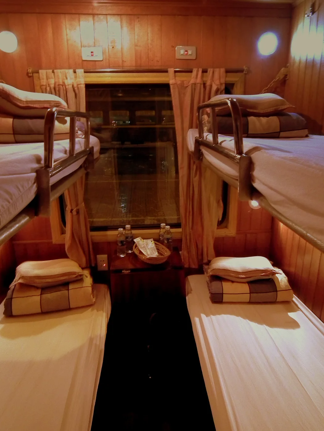 Interior of a four-berth soft sleeper compartment on a Vietnamese train, with two bunks either side and bedding laid out