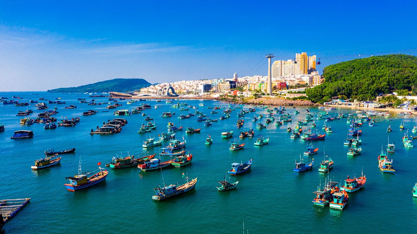 An Thoi harbour in southern Phu Quoc seen from the air, packed with blue fishing boats, with the buildings of Sunset Town along the shore behind
