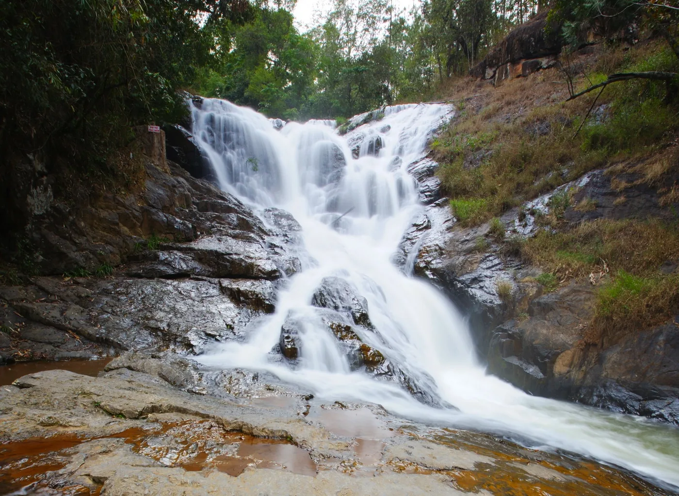 Datanla waterfall in the forest with a small wooden footbridge across the pool