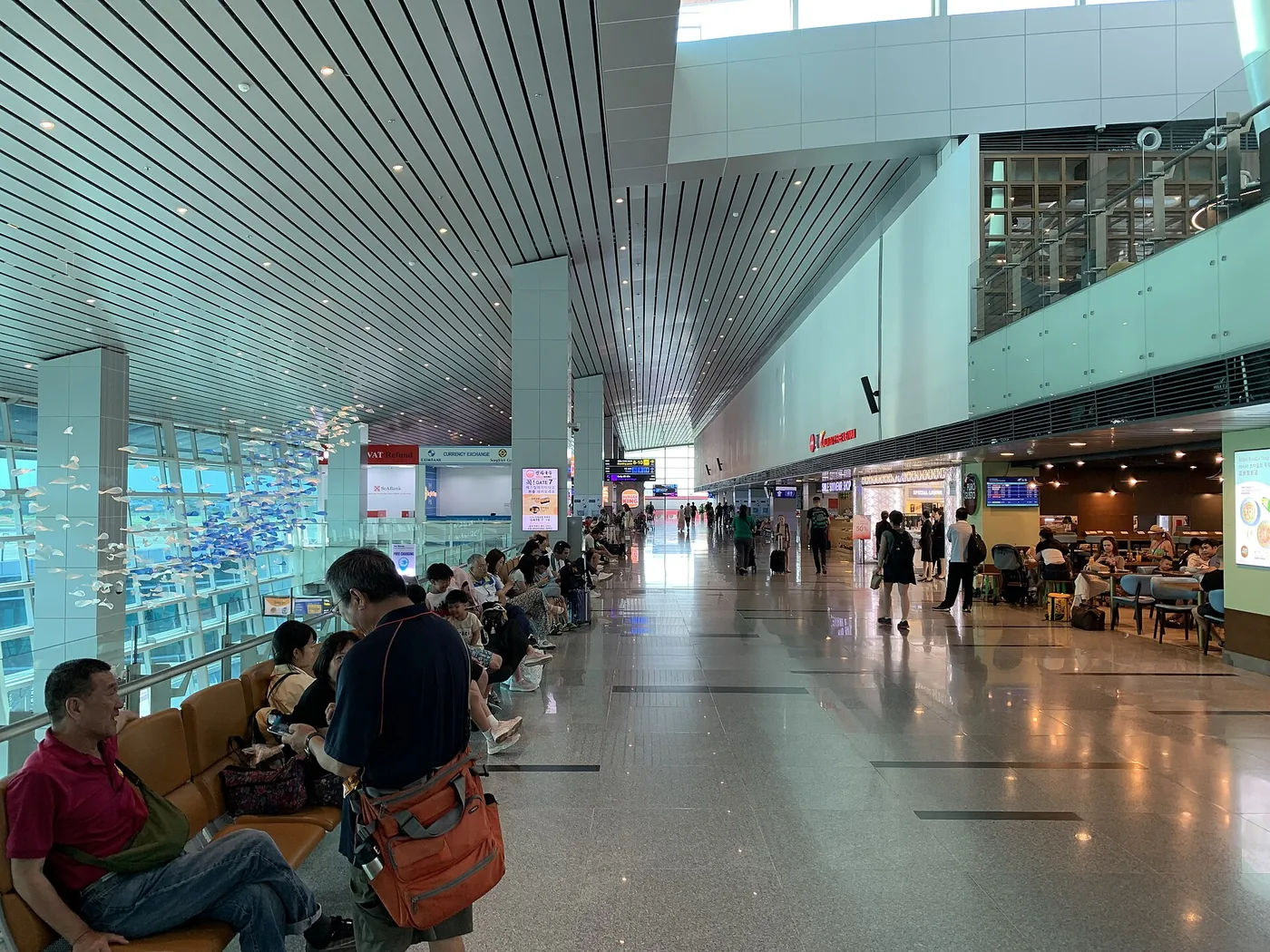 The concourse of the international terminal at Da Nang airport with travellers sitting along the seating rows