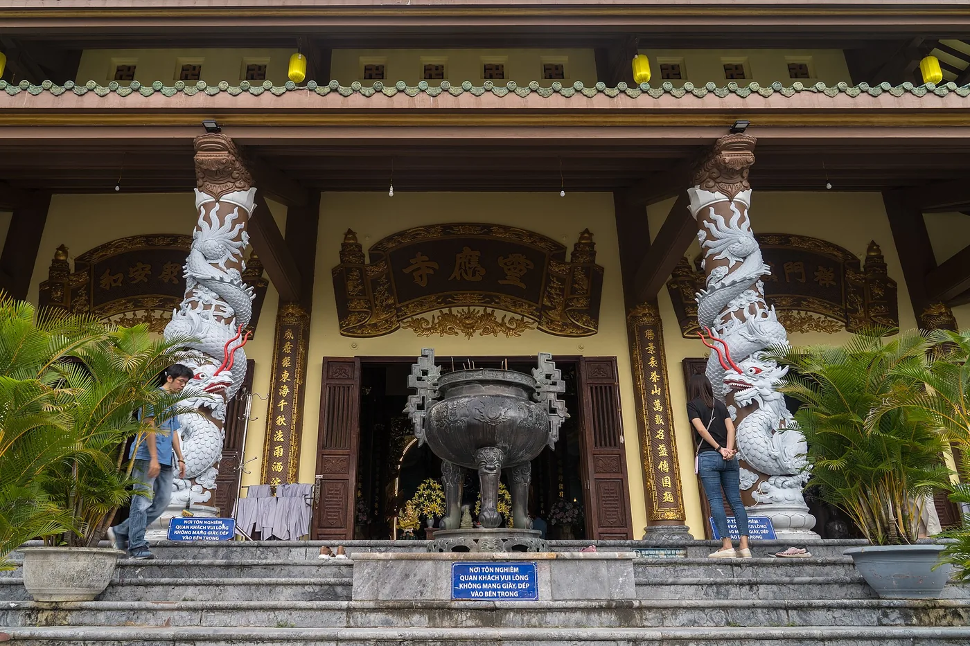 The front of the Linh Ung pagoda on the Son Tra peninsula with carved dragon pillars either side of the entrance and visitors on the steps