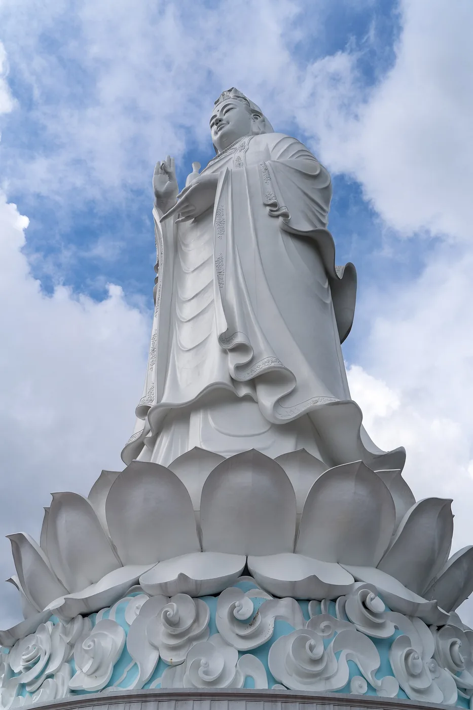 The white Lady Buddha statue at Linh Ung pagoda on the Son Tra peninsula in Da Nang, on a lotus pedestal against a cloudy sky