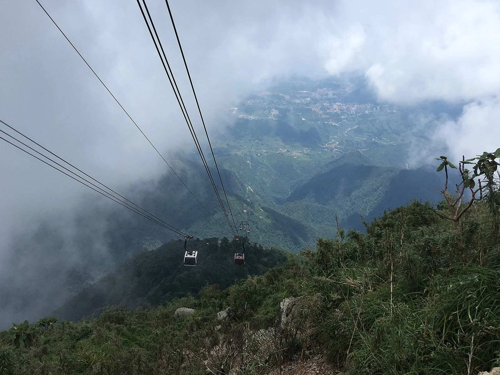 Fansipan cable car cables and a cabin disappearing into thick cloud above Sapa