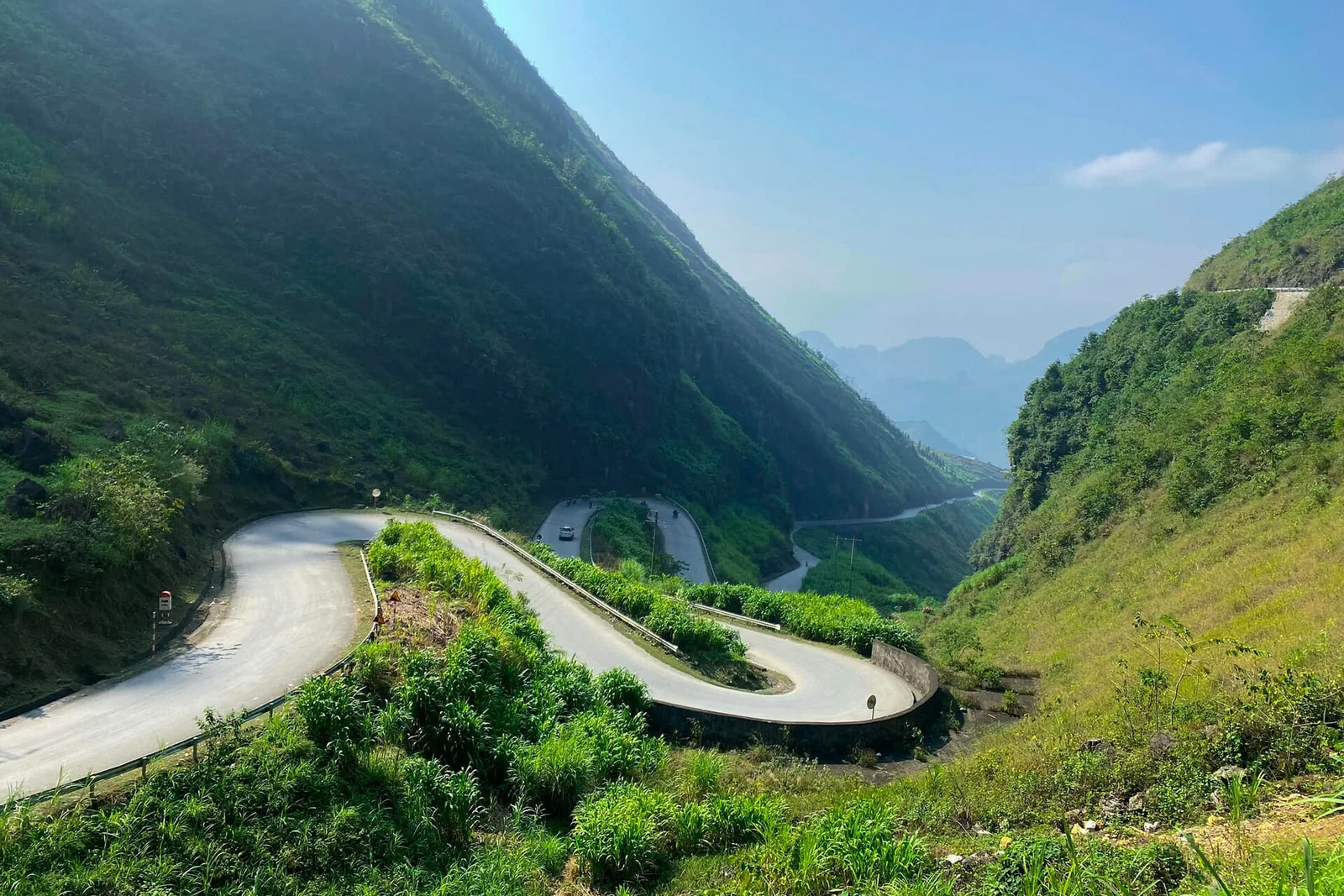 A winding mountain road curving around a steep hillside on the Ha Giang Loop