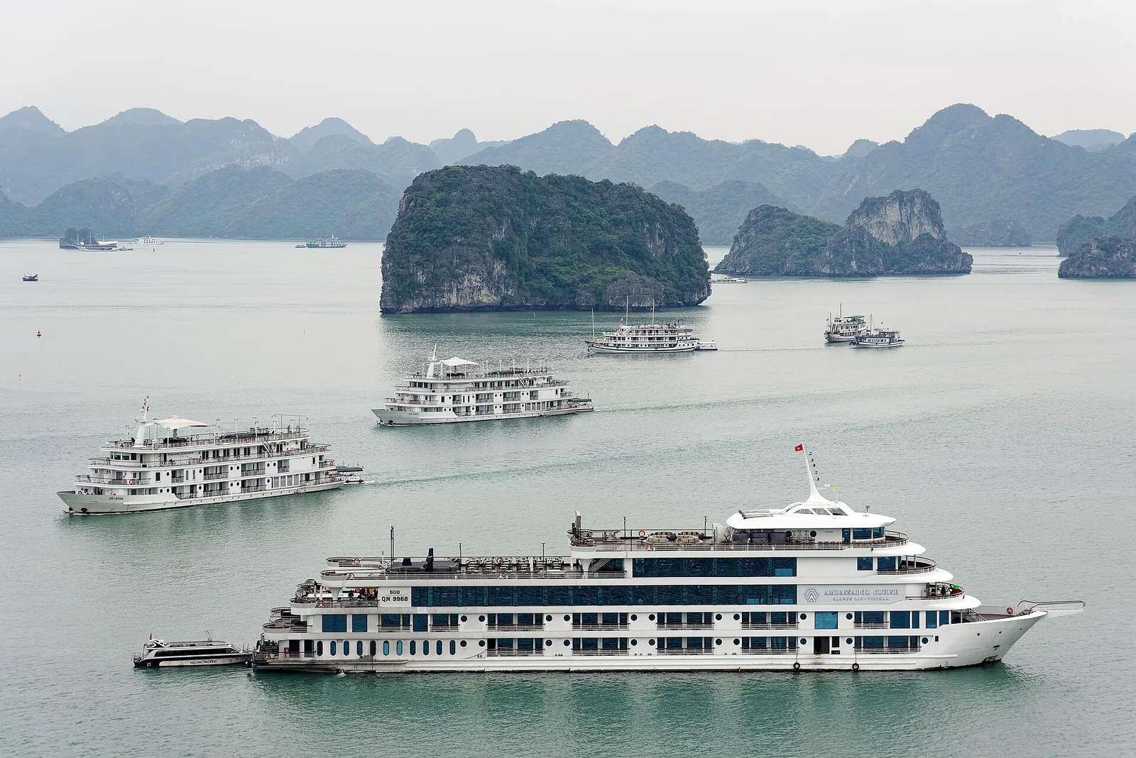 Several large white overnight cruise ships moored together in Ha Long Bay