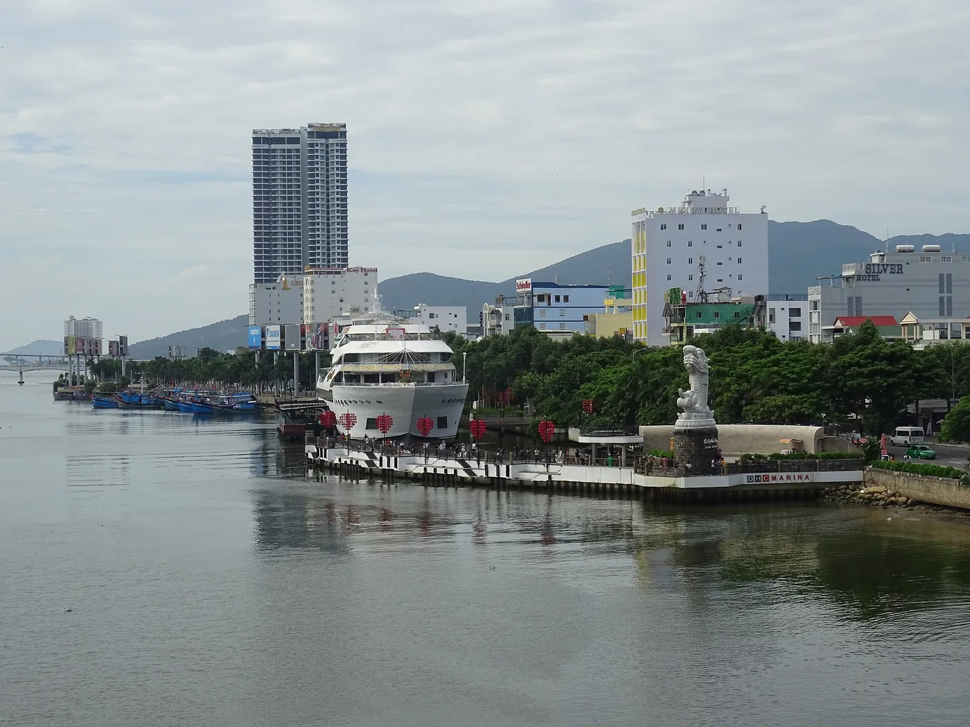A multi-deck cruise vessel alongside a pontoon on the Han River in Da Nang