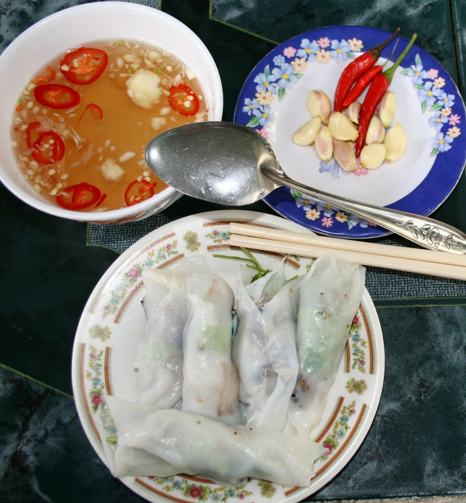 A plate of banh cuon steamed rice rolls with a small bowl of nuoc mam dipping sauce