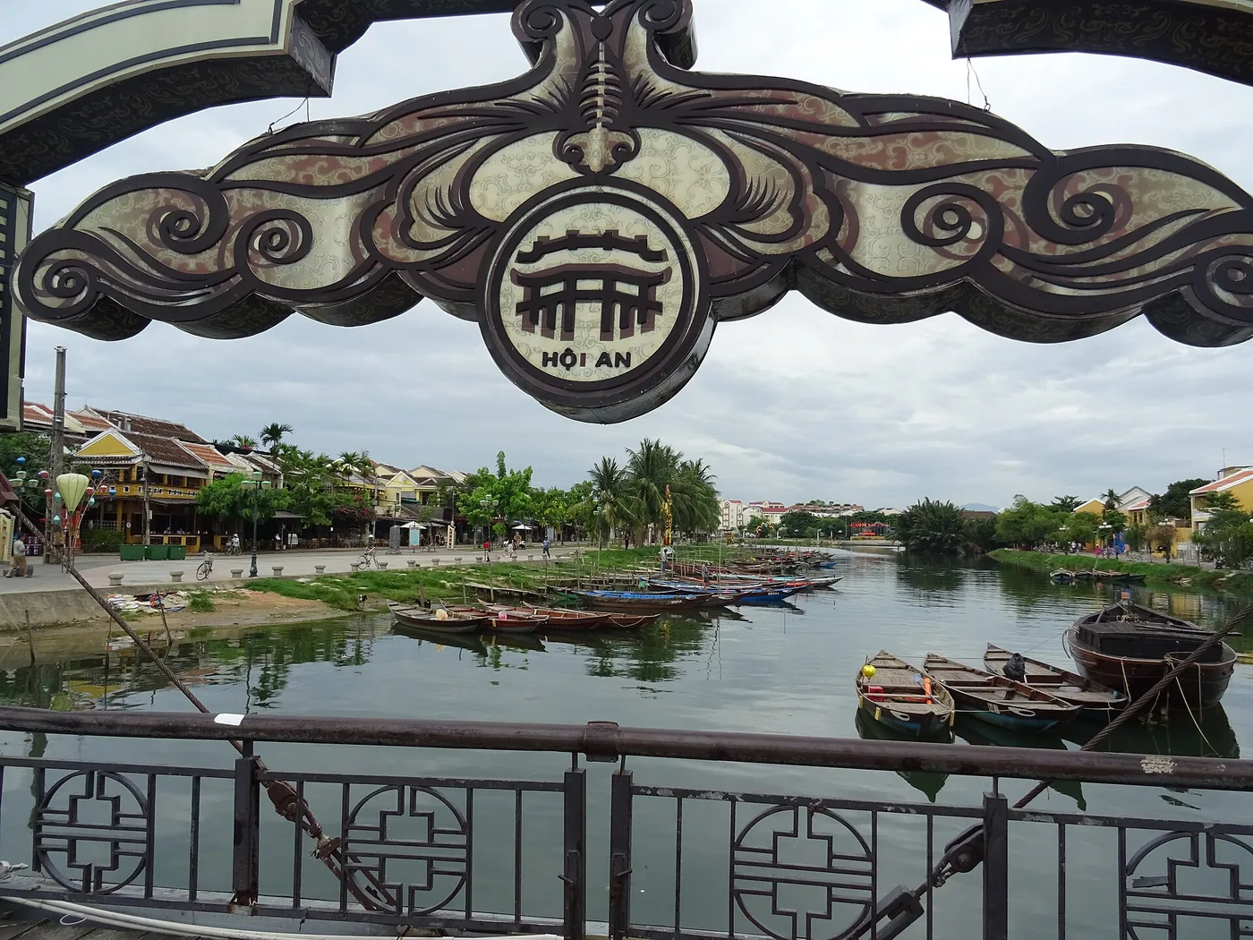 The Thu Bon river at Hoi An seen from a bridge, wooden boats moored along the bank and the old town on the far side