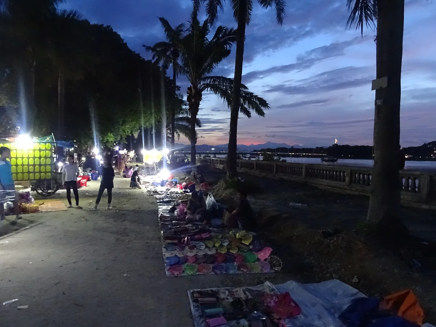 香江南岸步道上亮著燈的夜間攤位與往來人群