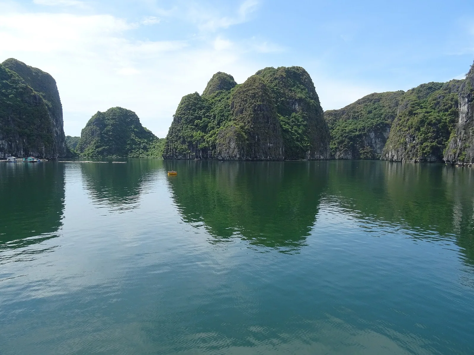 Limestone karst islands and flat calm water in Lan Ha Bay under a clear blue sky