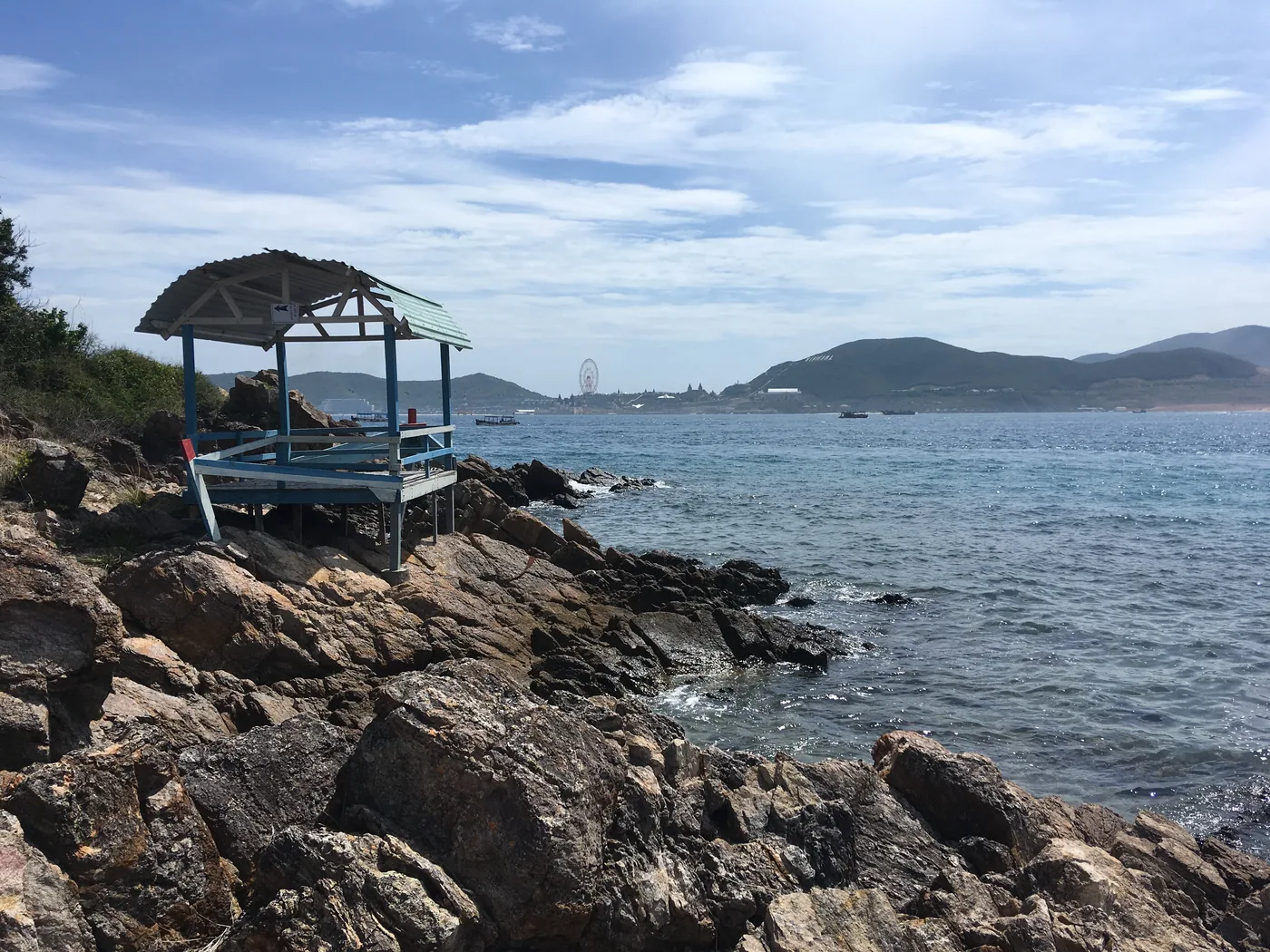 The rocky shore of Hon Mieu island with Nha Trang across the bay