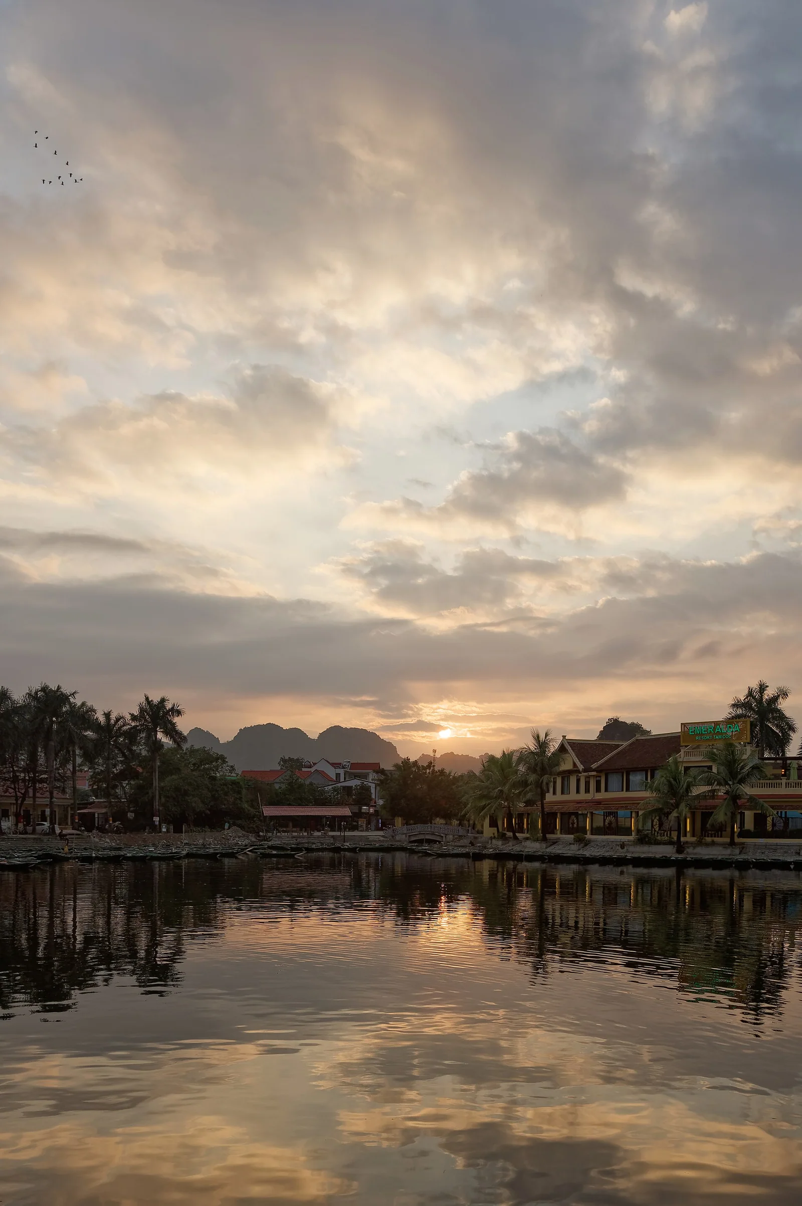Limestone peaks reflected in still water at Tam Coc in Ninh Binh at sunset