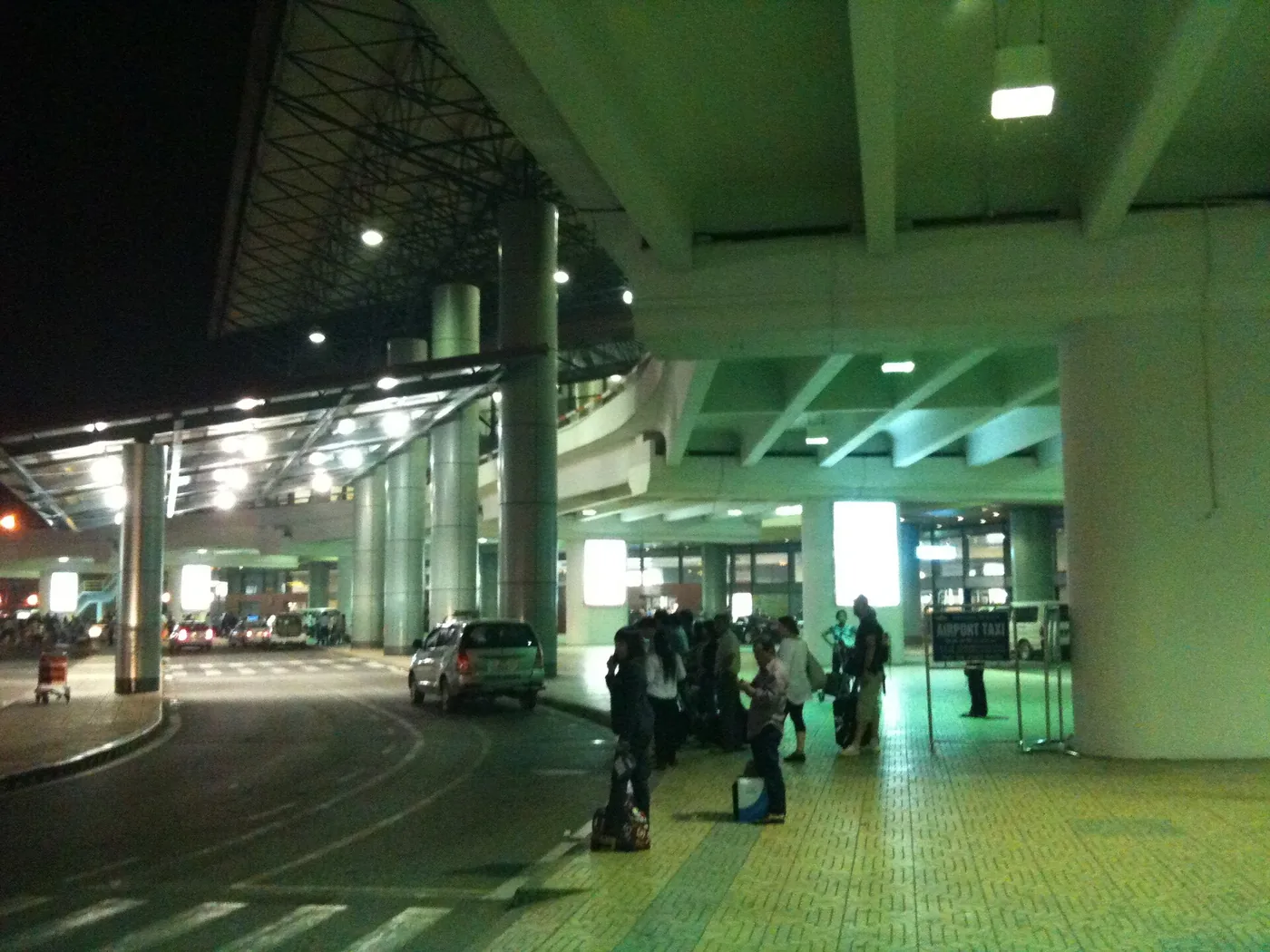 밤에 노이바이 공항 도착층 연석에서 짐을 들고 차를 기다리는 사람들
