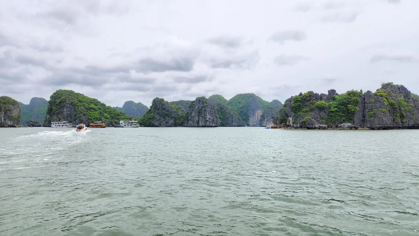 ランハ湾の石灰岩の島々と穏やかな海、左手に小さな船が数隻浮かんでいる ランハ湾の石灰岩の島々と穏やかな海、左手に小さな船が数隻浮かんでいる