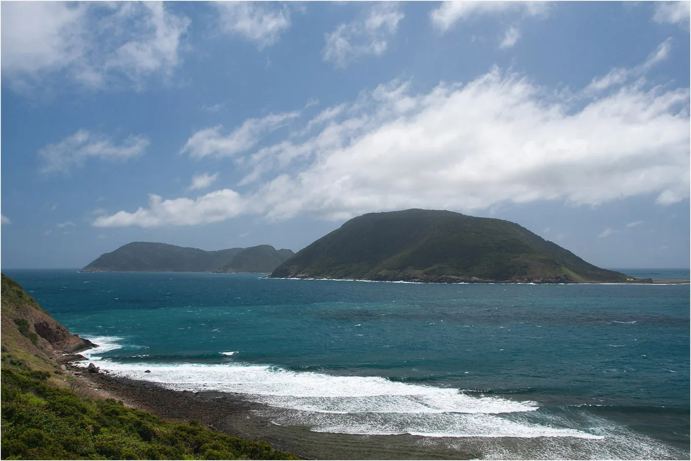 The sea and the green shape of Bay Canh island seen from a hillside