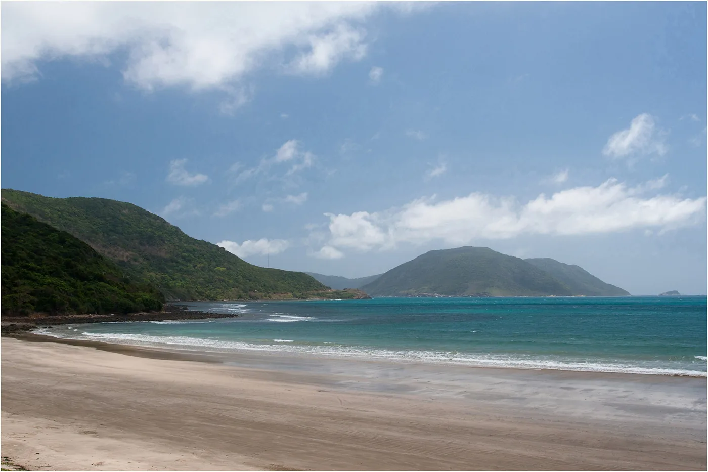 The long sandy curve of Dat Doc beach on Con Dao with green headlands at both ends