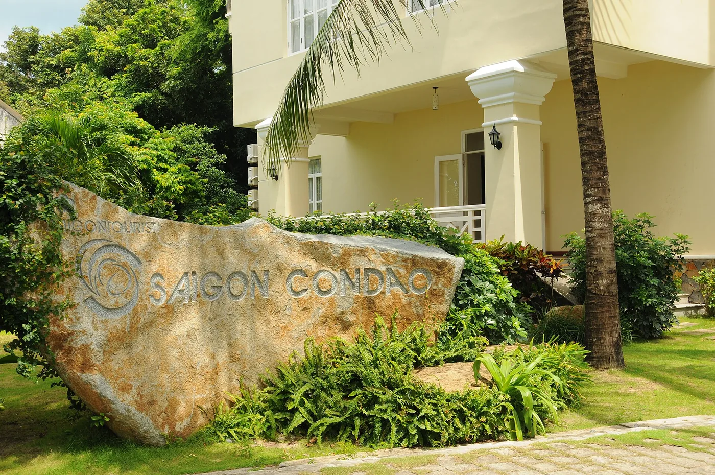The stone entrance sign of Saigon Con Dao Resort with the resort building behind it