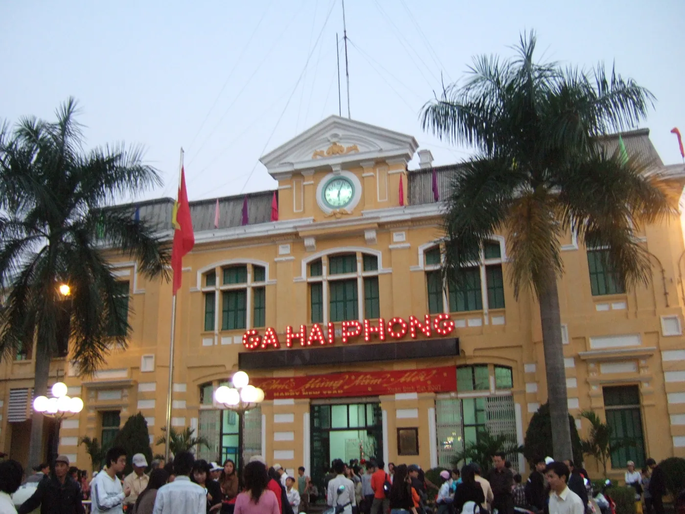 The yellow French-era Hai Phong railway station building with a crowd standing in front of it