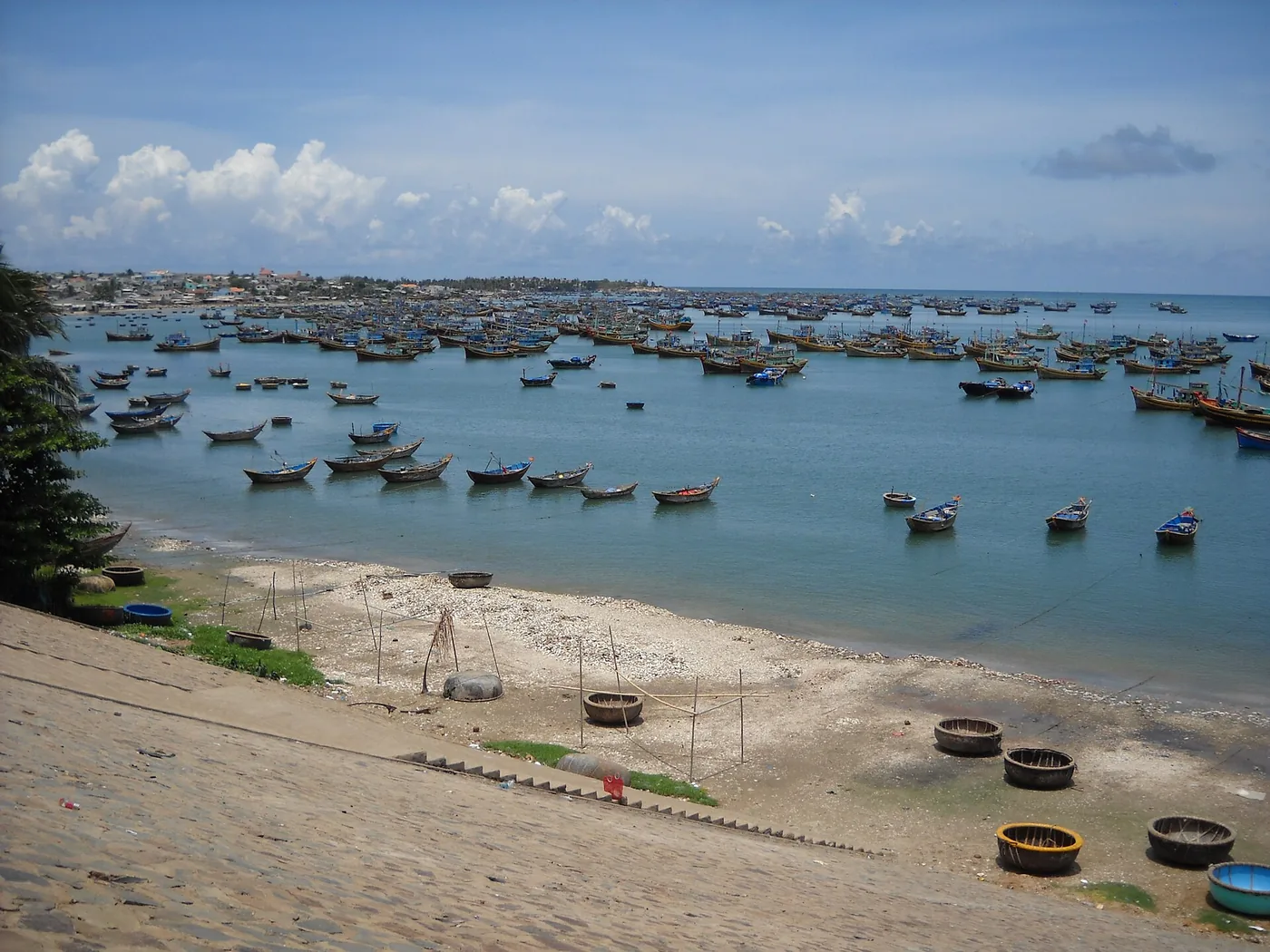 The bay at Mui Ne fishing village filled with moored boats and round basket boats on the sand The bay at Mui Ne fishing village filled with moored boats and round basket boats on the sand